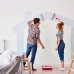 Young couple painting the interior wall in their new apartment